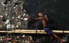 A boy plays in a polluted river after school at Pluit dam in Jakarta, Indonesia, June 5, 2009.