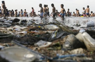 People paddle in the waters of Manila Bay amid garbage in the Philippines’ capital city on Easter Sunday, April 24, 2011.