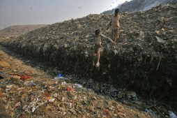 Waste collector Dinesh Mukherjee, 11, watches his friend jump over a puddle of toxic liquid at the Ghazipur landfill in New Delhi Nov. 10, 2011.