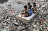 Children sitting on a makeshift raft play in a river full of rubbish in a slum area of Jakarta, Indonesia, in 2012.